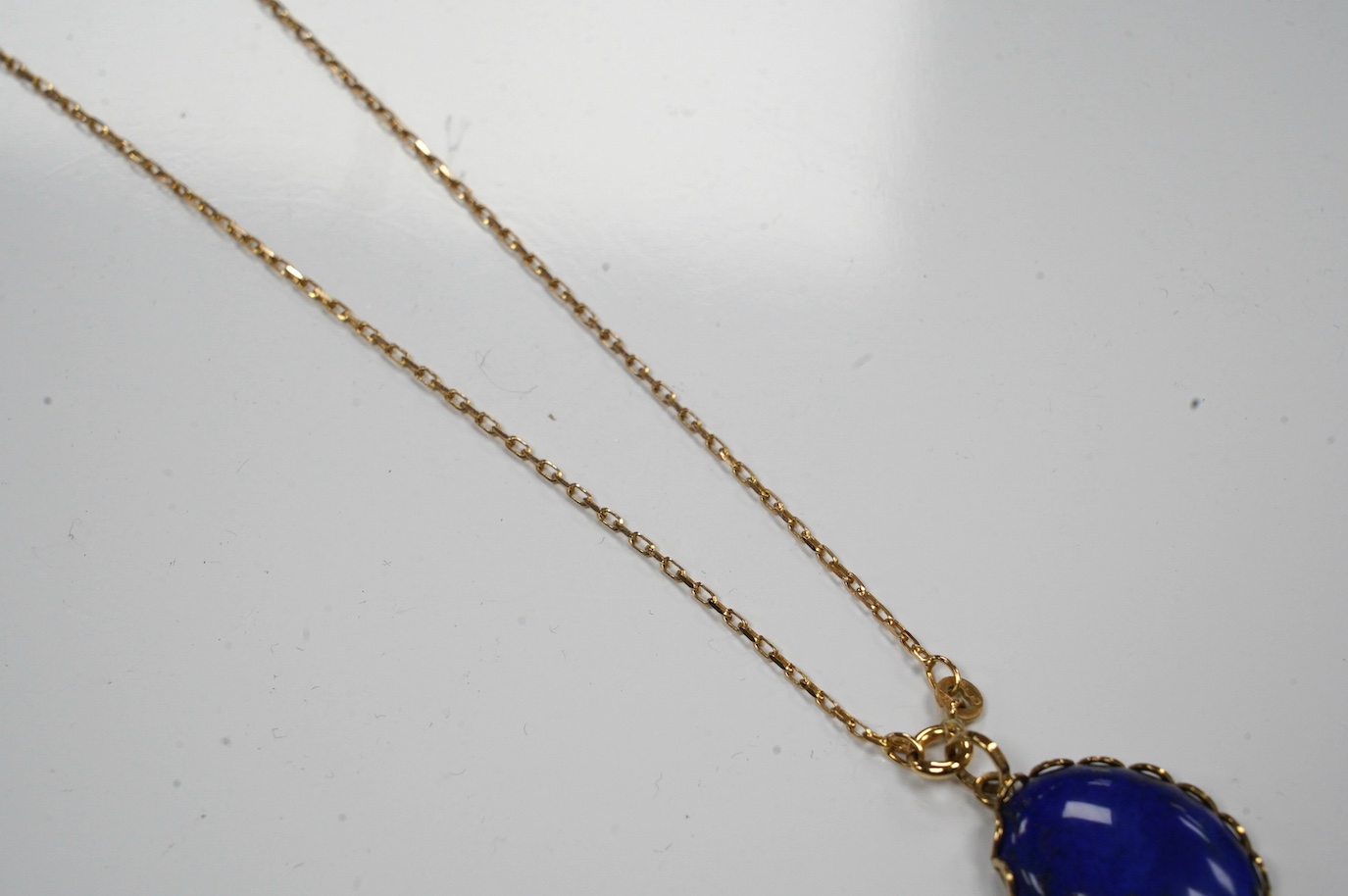 A modern 9ct gold mounted oval lapis lazuli pendant, 25mm, on a 9k fine link chain, 36cm, gross weight 8.2 grams. Condition - fair to good